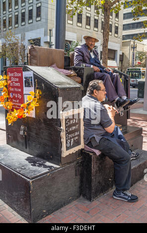 Two older men sit at an outdoor shoe shine stand on a sidewalk in downtown San Francisco, California. Stock Photo