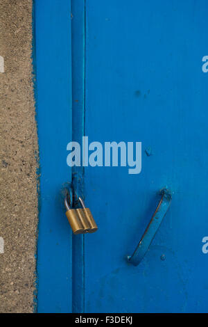 Golden padlock fasten on a  building  blue door Stock Photo