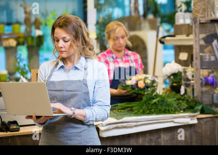 Female Florist Using Laptop In Flower Shop Stock Photo