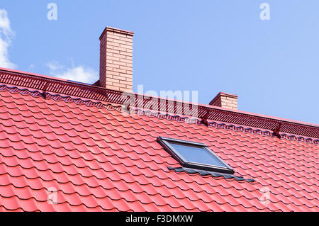 Brick chimney on red roof with mansard window Stock Photo