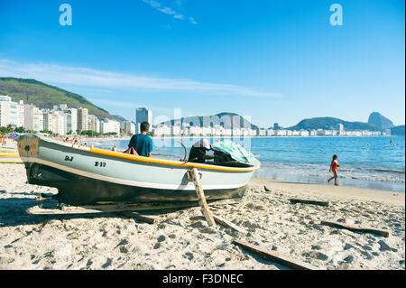 RIO DE JANEIRO, BRAZIL - FEBRUARY 3, 2014: Brazilian fishermen work from a traditional fishing boat on Copacabana Beach. Stock Photo