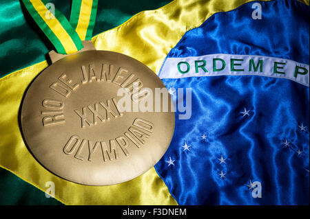 RIO DE JANEIRO, BRAZIL - FEBRUARY 3, 2015: Large gold medal commemorating the XXXI 31st Olympiad - 2016 Olympic Games on flag. Stock Photo
