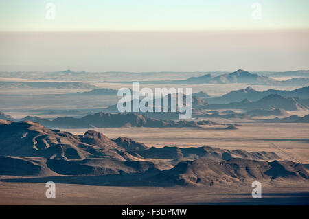 Isolated mountain ridges and C27 gravel road, edge of Namib Desert, coastal fog behind, aerial view, NamibRand Nature Reserve Stock Photo
