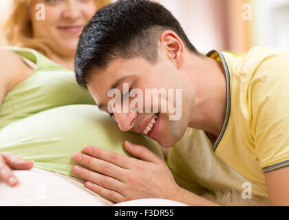 Young man strokes tummy of his pregnant woman. Careful husband with his pregnant wife. Stock Photo