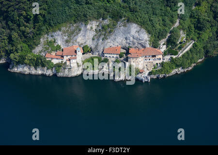 AERIAL VIEW. Monastery on a cliff face above the shore of Lake Maggiore. St Catherine Hermitage, Leggiuno, Province of Varèse, Lombardy, Italy. Stock Photo