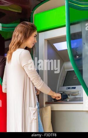 Young pretty woman at the ATM machine Stock Photo