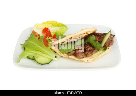 Fried minute steak in a flatbread kebab style with salad on a plate isolated against white Stock Photo