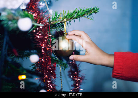 Child's hand touching ornament on Christmas tree Stock Photo