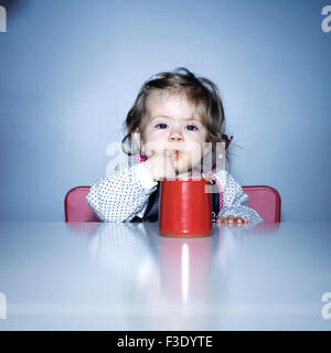 Baby girl licking food off finger Stock Photo