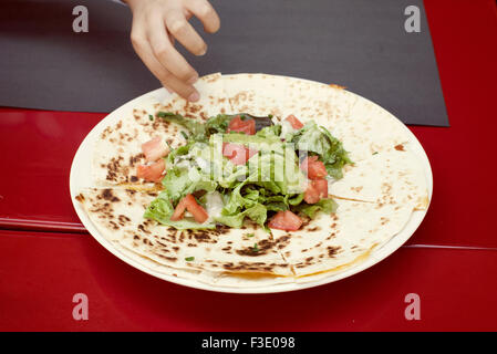 Child's hand reaching for quesadilla on plate Stock Photo