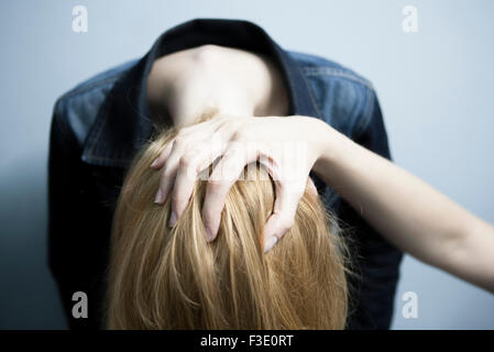 Person holding woman's head down Stock Photo