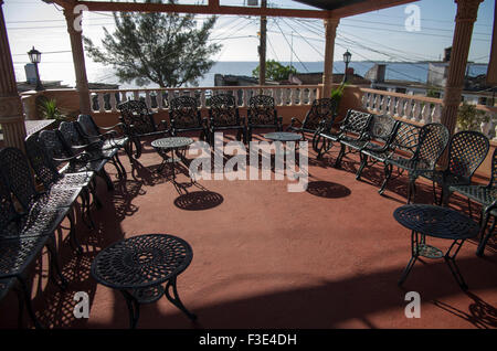 Long shadows of chairs cast in the bright sunlight on a balcony overlooking the sea in Play Larga on the island Republic of Cuba Stock Photo