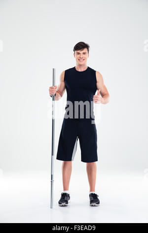 Portrait of a smiling fitness man holding barbell and showing thumb up isolated on a white background Stock Photo