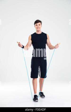 Full length portrait of a happy fitness man workout with jumping rope isolated on a white background Stock Photo