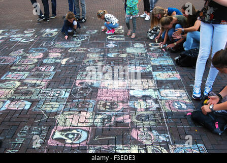 children drawing chalk faces in the street Stock Photo