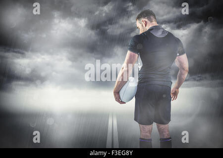 Composite image of tough rugby player holding ball Stock Photo