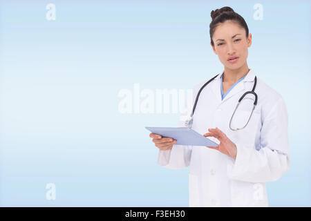 Composite image of focused doctor using her tablet pc Stock Photo