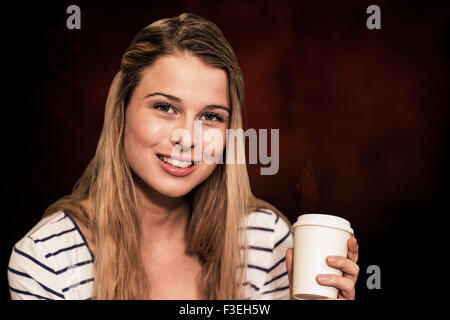 Composite image of portrait of smiling female student holding disposable coffee cup Stock Photo