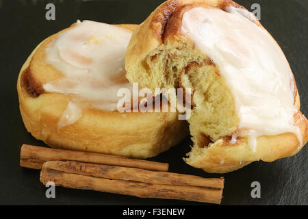 two iced cinnamon buns on a slate Stock Photo