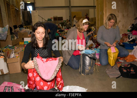 Volunteers in a shipping company's warehouse packing up donated items of clothing and other non-perishable items for shipping... Stock Photo