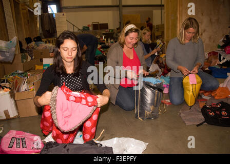 Volunteers in shipping company's warehouse packing up donated items of clothing & other items for shipping to Greece to help Syrian refugees... Stock Photo