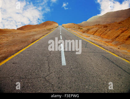A fragment of old asphalt road between desert hills before sunset (with vignette effect) Stock Photo