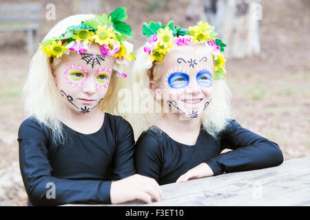 Twin girls in black clothing with sugar skull makeup smiling Stock Photo