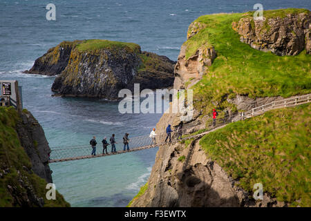 Tourists walk across the Carrick-a-Rede Rope Bridge along the north coast, County Antrim, Northern Ireland, UK Stock Photo