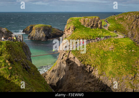 Tourists walk across the Carrick-a-Rede Rope Bridge along the north coast, County Antrim, Northern Ireland, UK Stock Photo