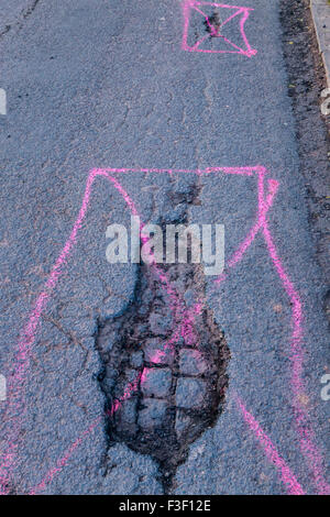 Potholes in a road with cobbles showing through. Each pothole is marked for repair. Nottingham, England, UK Stock Photo