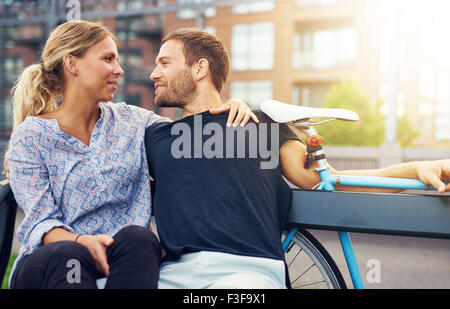 Loving couple sitting on bench in a city environment Stock Photo