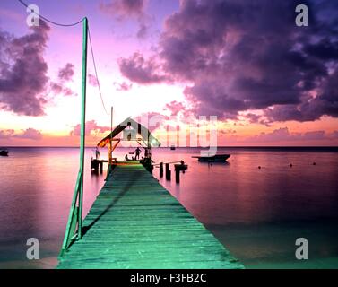 Locals sitting on the end of the jetty at Pigeon Point at sunset, Tobago, Trinidad and Tobago, Caribbean. Stock Photo