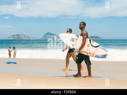 RIO DE JANEIRO, BRAZIL - FEBRUARY 20, 2014: Pair of young Brazilian surfers walk with surfboards along Ipanema Beach. Stock Photo