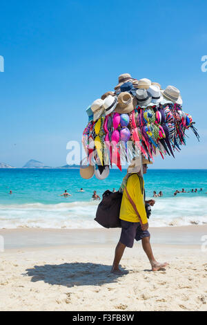 RIO DE JANEIRO, BRAZIL - JANUARY 22, 2014: Beach vendor selling bikinis and hats carries his merchandise on Ipanema Beach. Stock Photo