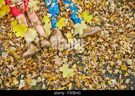 Kids legs in boots lying on autumn leaves Stock Photo
