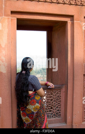 A long hair lady looking outside from the red fort window of Agra ; Uttar Pradesh ; India Stock Photo