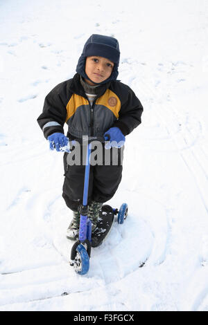 Small boy riding his tri wheel on snow ; Sweden MR#468 Stock Photo