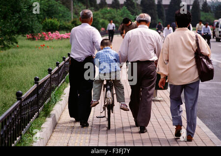 A kid gets driven around by his grand father on the streets of Beijing ; China Stock Photo