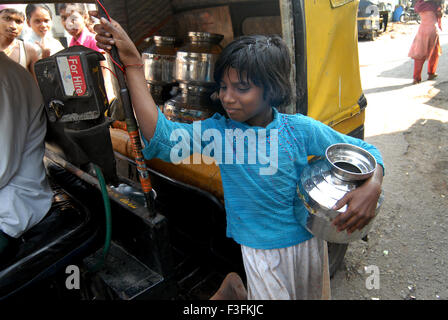 A young girl fill drinking water in stainless steel containers in a rickshaw at a slum in Chembur ; Bombay now Mumbai Stock Photo