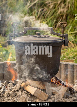 Black cast-iron kettle with fare placed on fire Stock Photo