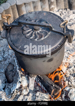Black cast-iron kettle with fare placed on fire Stock Photo