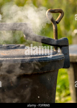 Black cast-iron kettle placed on fire Stock Photo