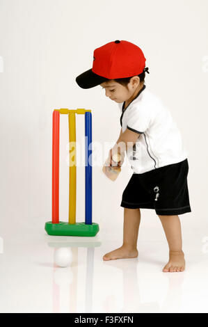 Indian Boy swinging the bat to hit the ball playing cricket ; MR Stock Photo