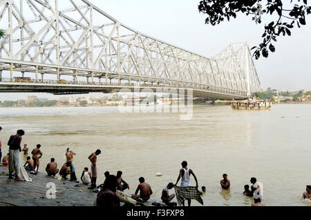 People bathing on ghat of hooghly river at Howrah bridge (Rabindra Setu) ; Calcutta now Kolkata ; West Bengal ; India Stock Photo