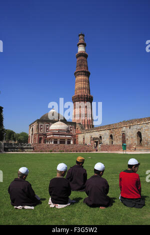 Children doing Namaz in front of Alai Darwaza ; Imam Zamin's tomb Qutab Minar red sandstone tower ; Indo Muslim art ; Delhi Stock Photo