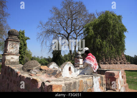 Muslim boy talking on mobile phone in Qutab Minar Complex ; Delhi sultanate ; Delhi ; India UNESCO World Heritage Site