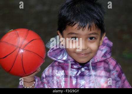 Child playing with ball in rain, India, Asia Stock Photo