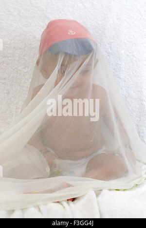 Indian baby boy child naughty hiding in transparent cloth diaper red blue color cap white background - MR#152 - RMM 134440 Stock Photo