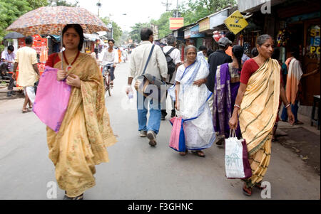 Indian women in traditional Bengali sari holding umbrella Dakshineshwar market street Calcutta Kolkata West Bengal India Stock Photo