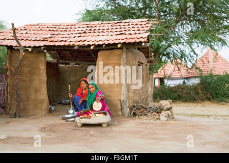 Women cooking food on a wood fired earthen stove outside her house Kutch ; Gujarat ; India Stock Photo